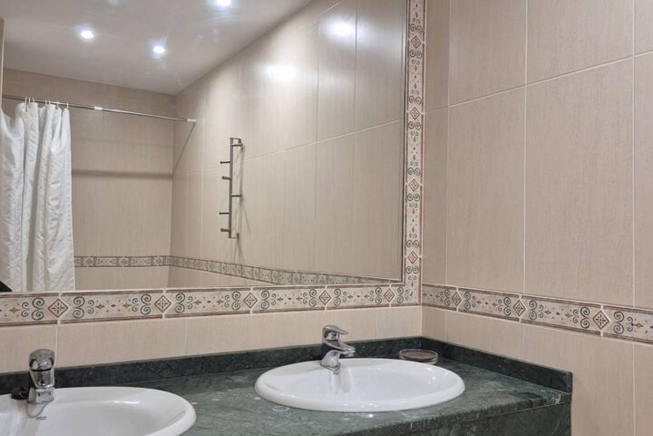 A bathroom with two sinks, a mirror, and a shower curtain.