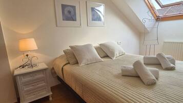 A bedroom with a bed, pillows, a nightstand, a lamp, and a window with a view.