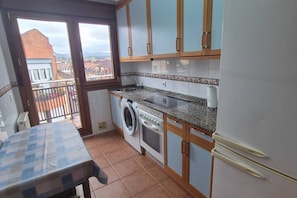 A kitchen with a washing machine, oven, and a dining table.