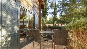 Un patio con mobiliario de mimbre, un ventanal de vidrio y vistas del jardín circundante.