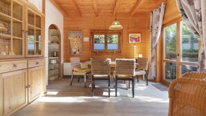 Un interior de madera con una zona de comedor, sillas de mimbre, una mesa y un armario.