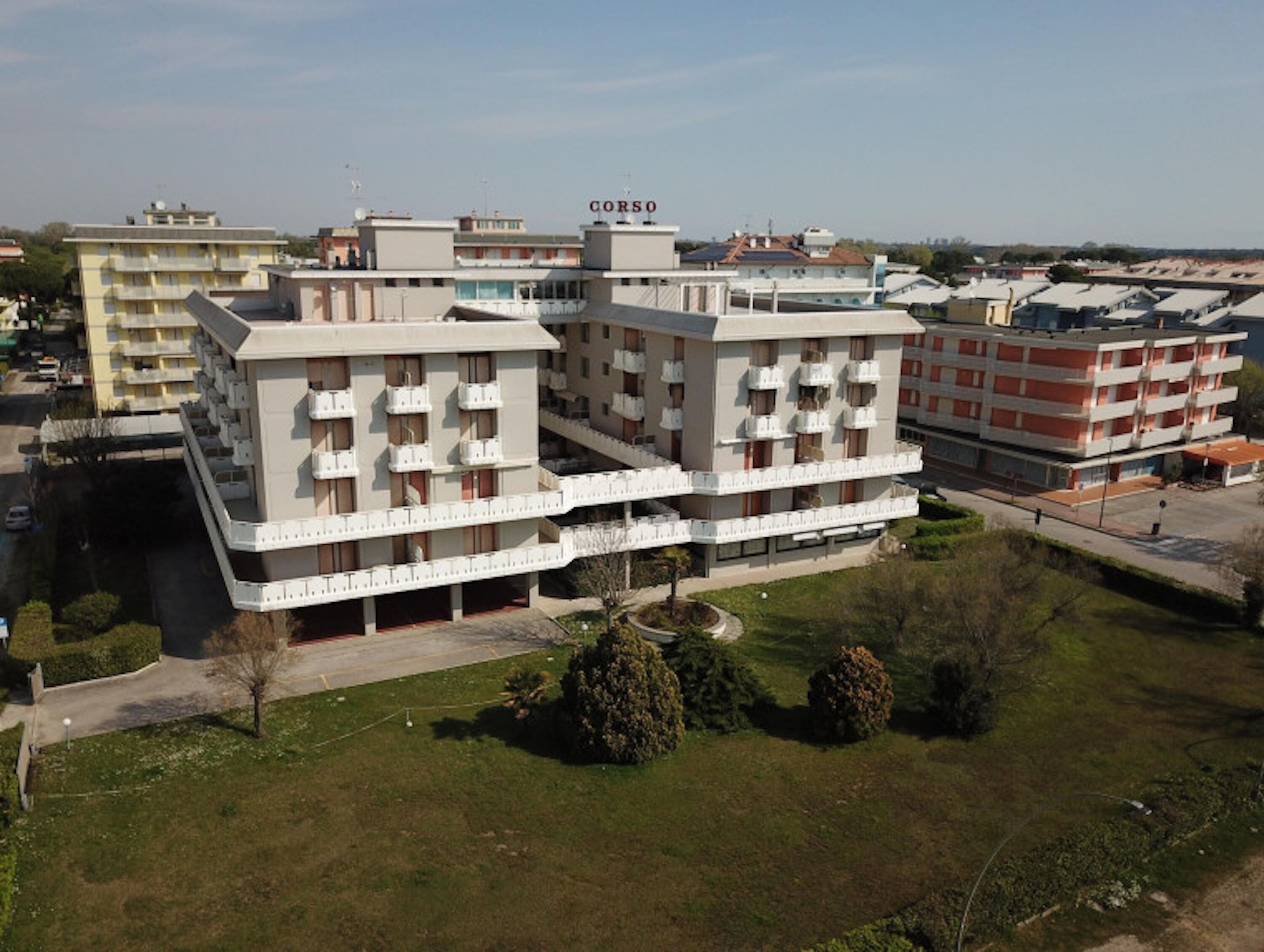 A multi-story hotel with a modern architectural design, featuring balconies on each floor and a central courtyard.