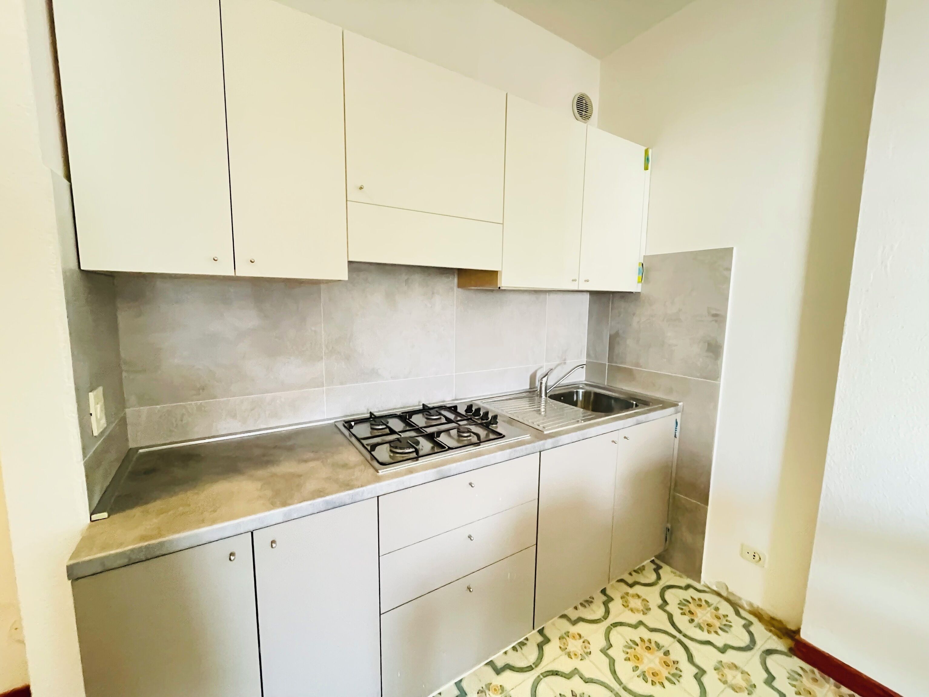 Una cucina con piano cottura a gas, lavello e mobili bianchi.
