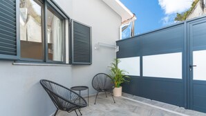 A balcony with two chairs, a potted plant, and a grey door. - Breeze House 2 by Atlantic Holiday (Caniço)