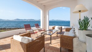 A terrace with wicker furniture, a glass table, and a potted plant. - Villa 'Punta Marina' with sea views, private terrace and Wi-Fi (Illes Balears)