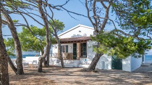 A white building with a tiled roof, surrounded by trees, near a body of water. - Villa 'Punta Marina' with sea views, private terrace and Wi-Fi (Illes Balears)