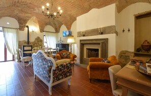 A cozy living room with a fireplace, a television, and a stone wall.