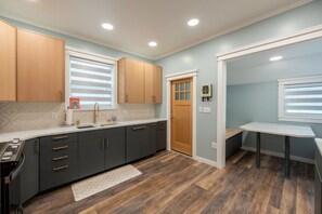 A modern kitchen with dark grey cabinets, a white countertop, and a wooden floor. - Luxury Downtown Juneau Home • Walk Everywhere • Boutique • Steps to Trails (Juneau)