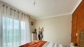 A bedroom with a bed, a radiator, a wardrobe, and a window with curtains. - Gîte / furnished 3-bedroom house with veranda and garden - available 13/09 → 15/10 (Lagor)