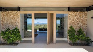 Une entrée moderne avec un mur en pierre, des portes en verre et une vue sur un paysage montagneux.