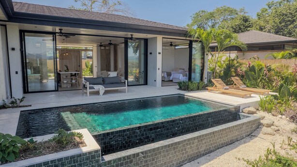 Une maison moderne dotée d’une piscine, d’un patio couvert et d’un jardin.