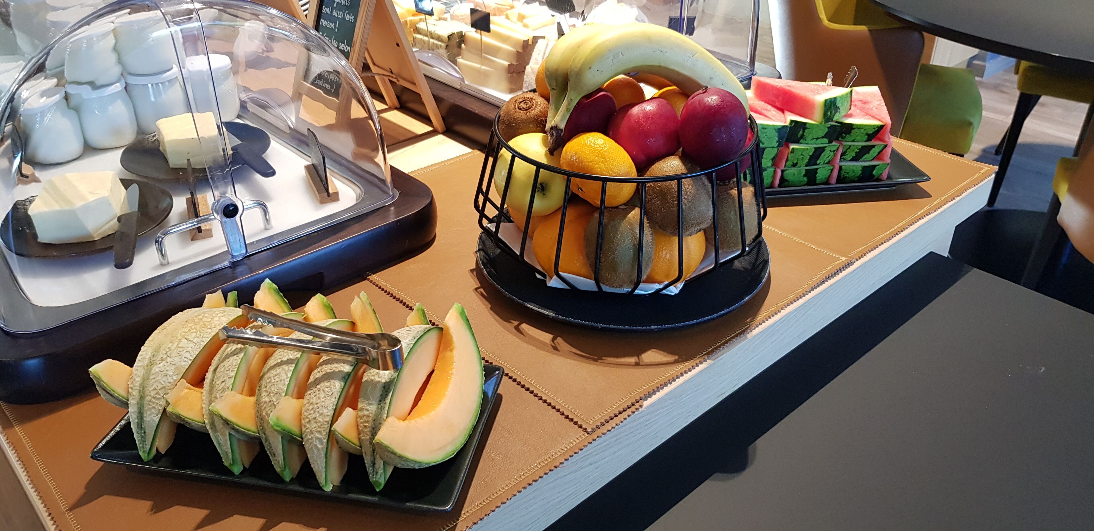 A buffet with various food items including fruits, vegetables, and cheeses.