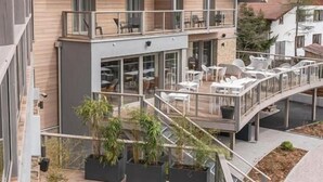 A modern building with multiple balconies, outdoor seating areas, and potted plants. - Hôtel Interlaken Lounge Bar & SPA (Xonrupt-Longemer)
