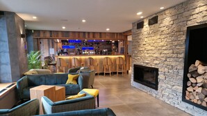 A bar area with seating, a stone fireplace, and a bar counter with a wooden backdrop. - Hôtel Interlaken Lounge Bar & SPA (Xonrupt-Longemer)