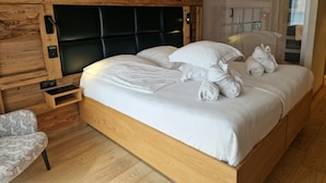 A wooden-framed bed with white bedding, a bedside table, and a chair. - Hôtel Interlaken Lounge Bar & SPA (Xonrupt-Longemer)