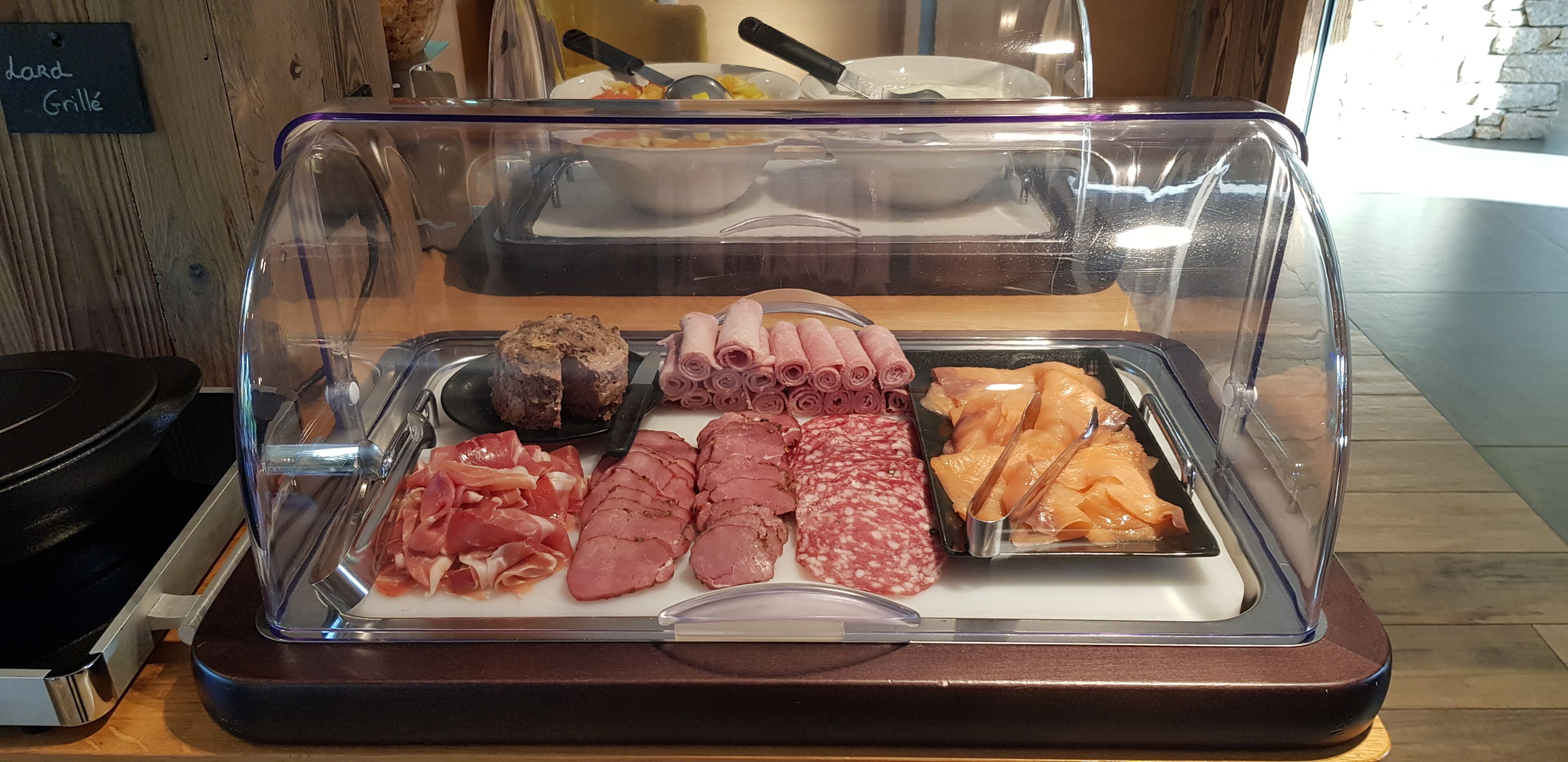 Exhibición de alimentos con diferentes carnes y un letrero que indica 'Standard Grille'.