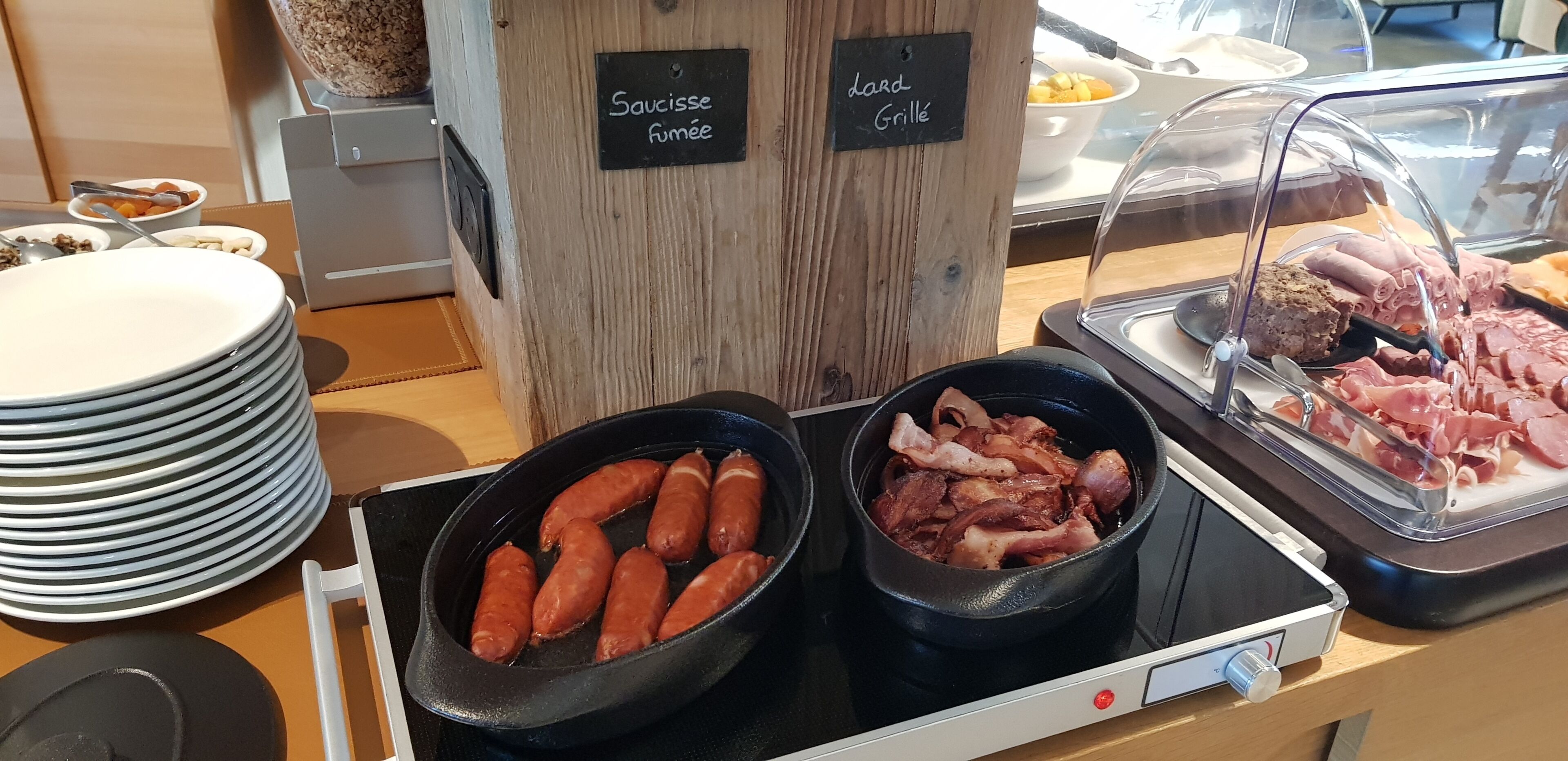Un buffet avec des présentoirs clairement identifiés pour les saucisses et les viandes grillées.