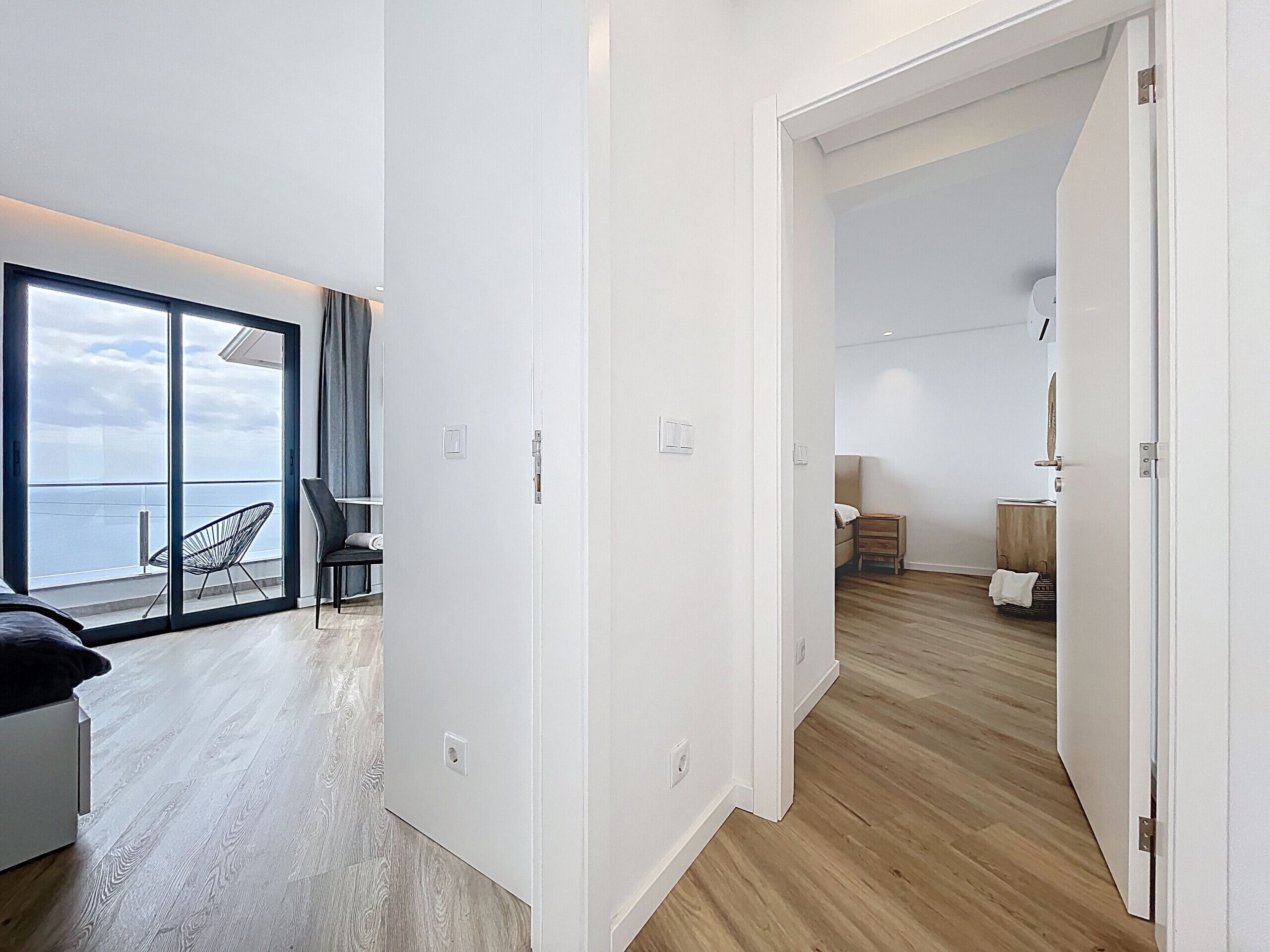 A modern apartment with a balcony, a dining area, and a bedroom.