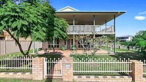 Ein zweistöckiges Haus mit Balkon, einem eingezäunten Garten und einem Baum.