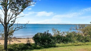 A coastal landscape with a tree, beach, and clear blue sky. - Welcome to Cockatoos View (Point Vernon)