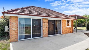 A single-story house with a tiled roof, large sliding glass doors, and a covered patio area. - Welcome to Cockatoos View (Point Vernon)
