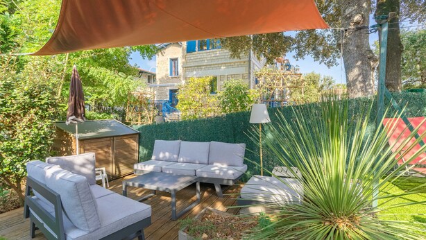 Eine Terrasse mit Gartenmöbeln, einem Blumentopf und einer Hecke.