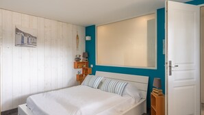 Ein Schlafzimmer mit einem Bett, einem Nachttisch, einer Lampe, einem Wandregal und einer Tür.
