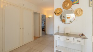 Ein Zimmer mit einem weißen Kleiderschrank, einem Schminktisch mit Spiegel und einer Wand mit Hüten und einem gerahmten Bild.