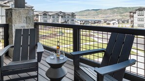 Ein Balkon mit Adirondack-Stühlen, einem kleinen Tisch und einer Whiskey-Flasche.