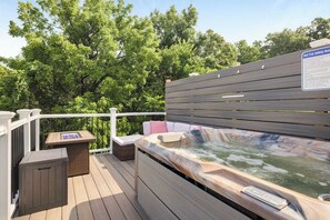 A hot tub on a wooden deck with a safety rule sign, surrounded by lush greenery. - Riverview Retreat - Pool, Hot Tub, and Mtn Views! (Harpers Ferry)