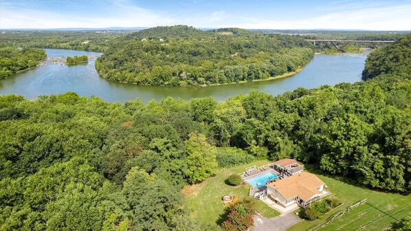 A large house with a swimming pool, surrounded by dense forest and a river. - Riverview Retreat - Pool, Hot Tub, and Mtn Views! (Harpers Ferry)