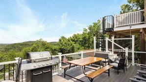 Eine Terrasse im Freien mit Grill, Sitzgelegenheit und einer Treppe zu einer erhöhten Ebene.
