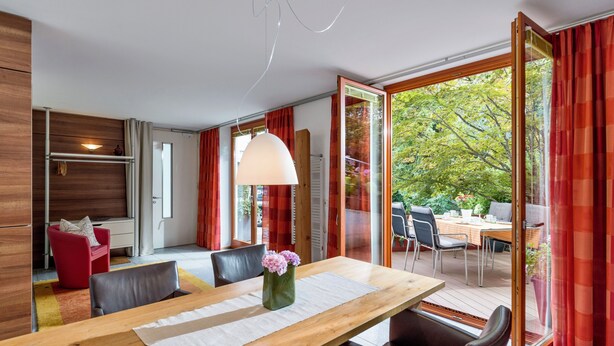 A modern dining area with a wooden table, chairs, and a vase with flowers. - Currently not available via Fewo direkt (Söll)