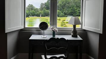 Ett skrivbord med en stol, en lampa och en vas med blommor.