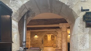 An arched hallway with stone walls and wooden flooring, leading to a room with a fireplace and a stone archway. - Château de Valesne (Saché)