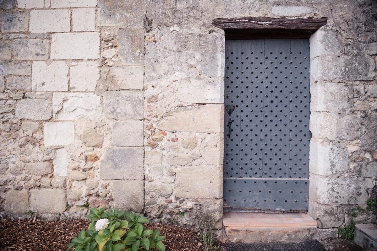 A stone wall with a metal door featuring a diamond-patterned design.