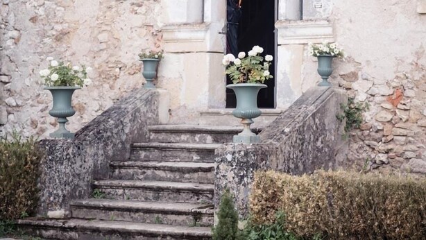 A stone building with a set of stairs leading to a doorway. There are two green lanterns on either side of the door. - Château de Valesne (Saché)