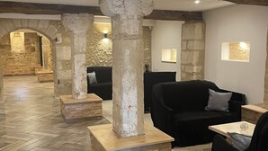 A spacious lobby with herringbone patterned flooring, stone columns, and black leather sofas. - Château de Valesne (Saché)
