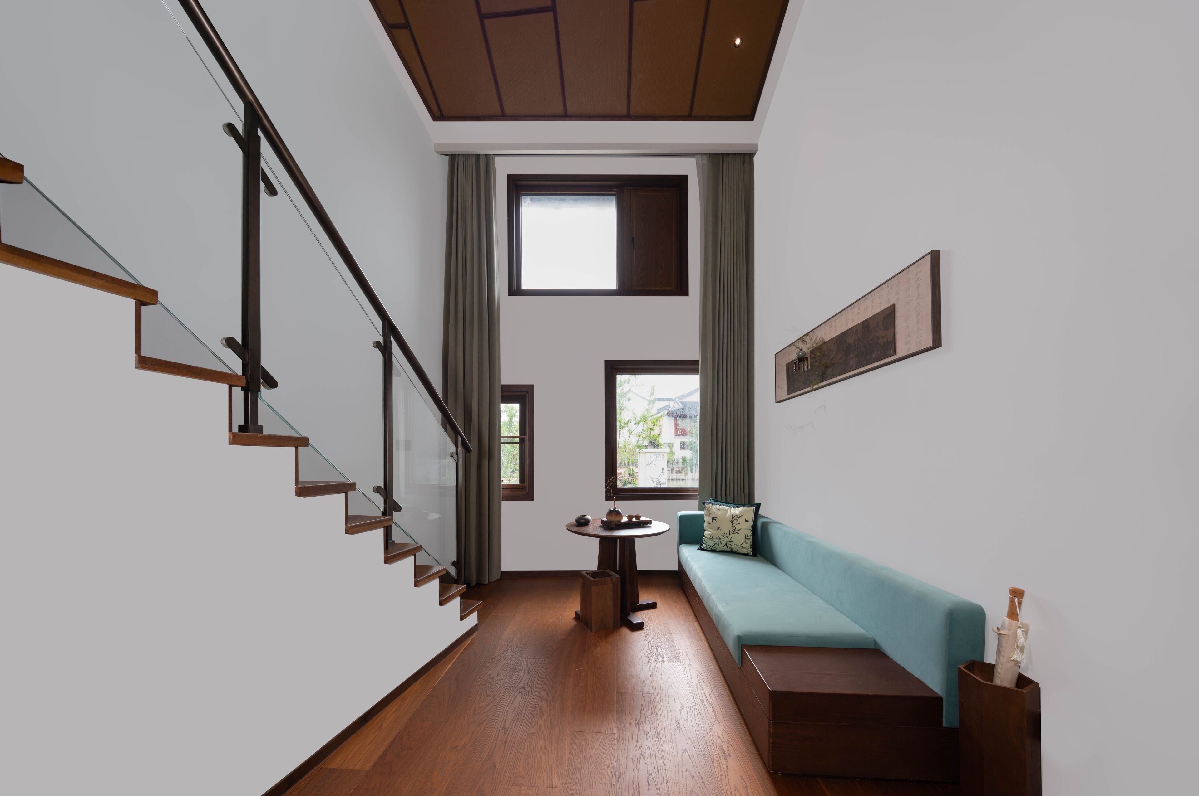 Een modern interieur met een trap, een ronde tafel, een bank en een schilderij aan de muur.