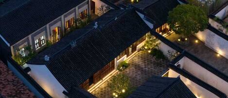 A traditional courtyard with multiple buildings, each featuring dark tiled roofs and white walls.