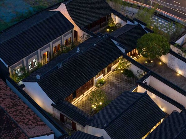 A traditional courtyard with multiple buildings, each featuring dark tiled roofs and white walls.
