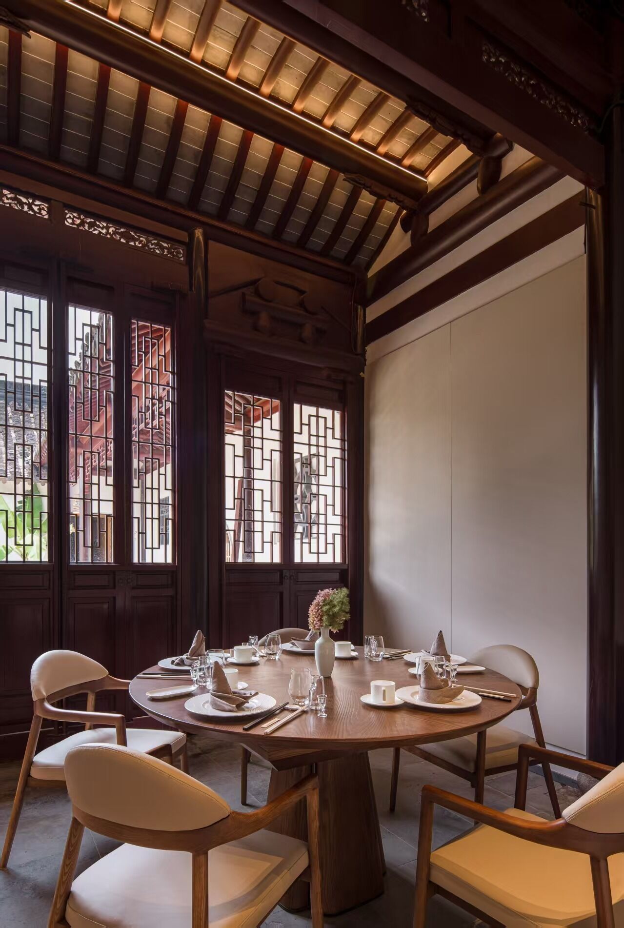 Un coin repas avec une table ronde dressée pour quatre personnes, des chaises en bois et un vase décoratif.