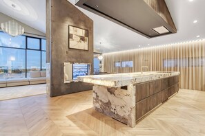 A modern kitchen with a marble island, large windows, and a city view. - Nordic Retreat by the Water Hot Tubs & Northern Lights (Garðabær)
