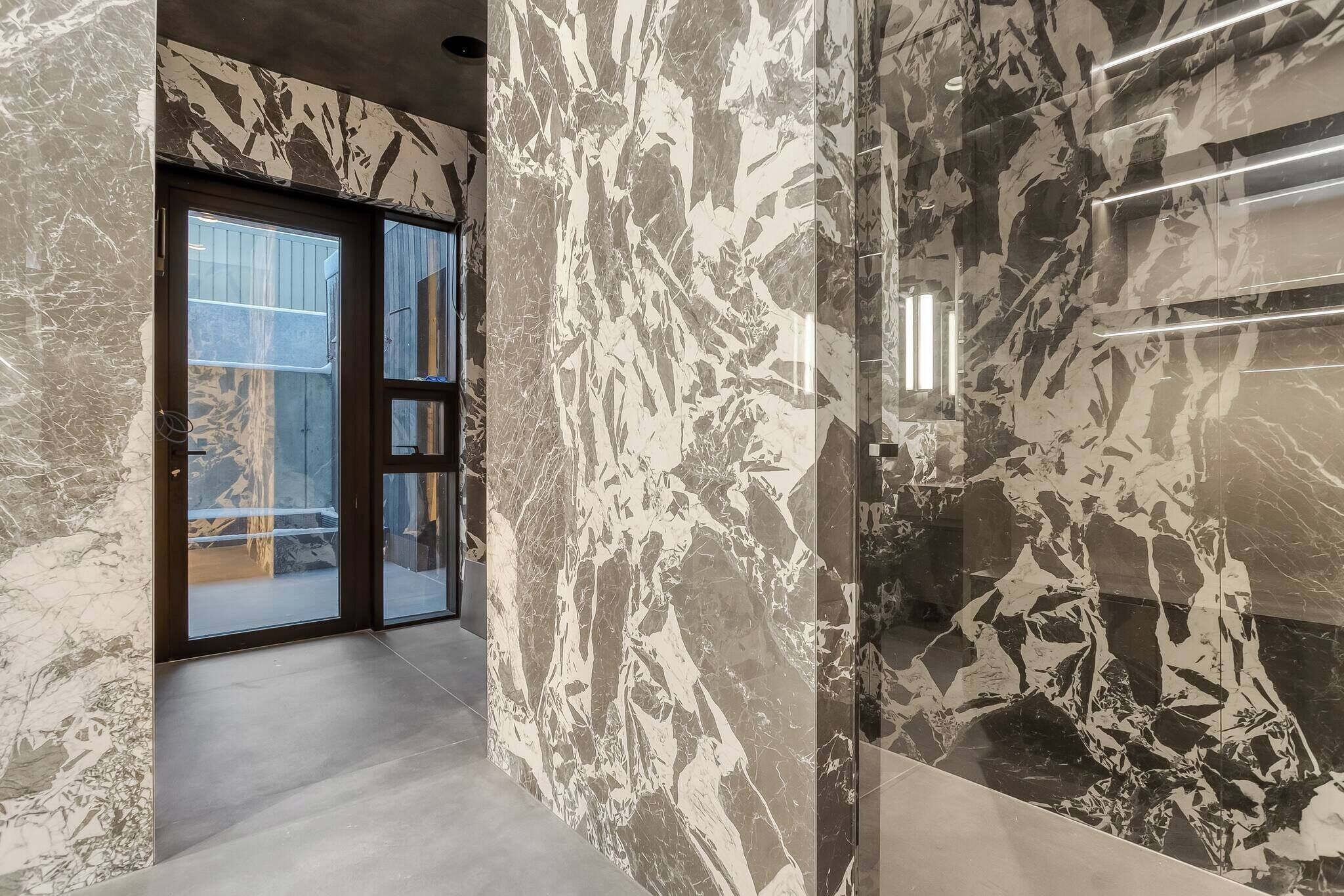A hallway with marble walls and a glass door leading to an outdoor area.