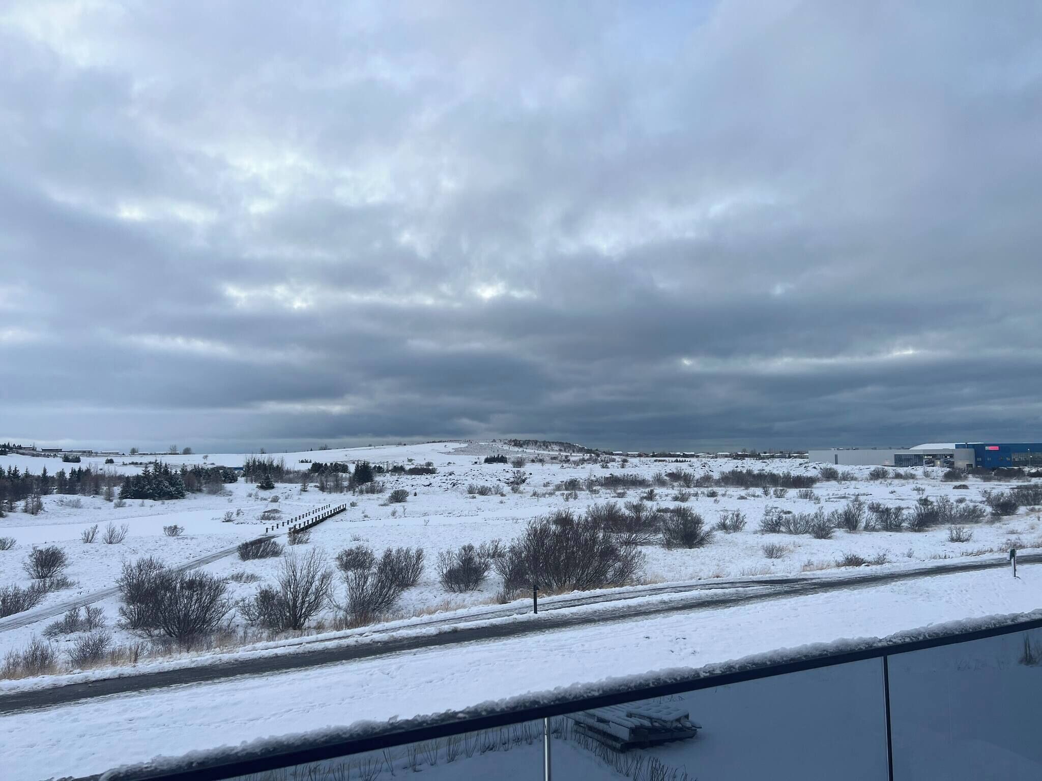 A snowy landscape with a road and a building in the distance.
