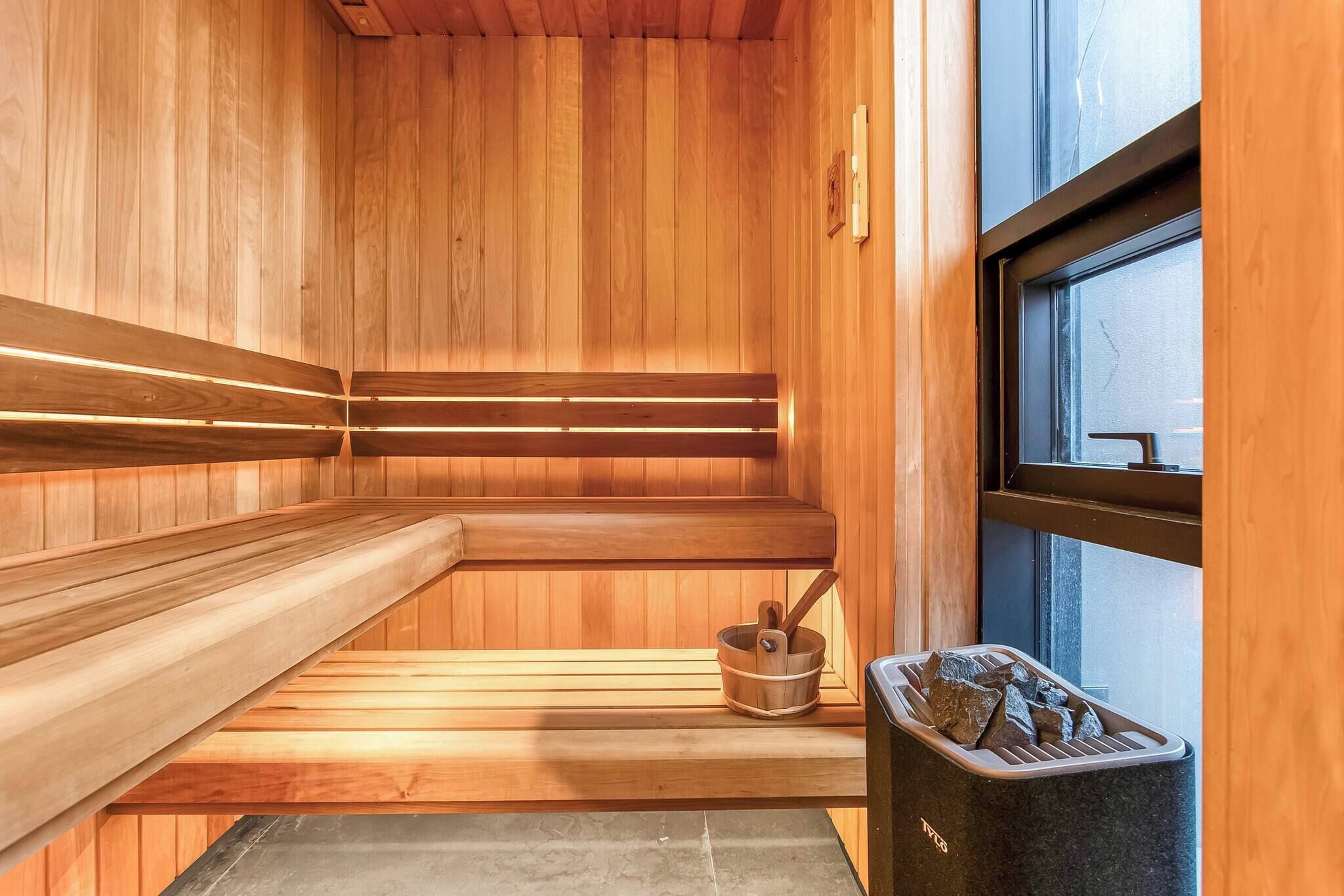 A sauna with wooden benches, a stone basin, and a window.