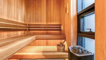 A sauna with wooden benches, a stone basin, and a window.