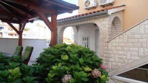 A covered outdoor seating area with a stone archway, air conditioning units, and a staircase leading to an upper level. - comfortable family-sized apartment for 4 people Ines 2 (Pula)