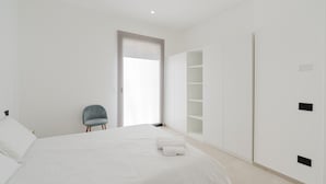 Una camera da letto dal design minimalista con un letto, una sedia e scaffali a muro.