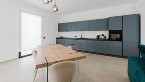 A modern kitchen with a wooden table and chairs, grey cabinets, and pendant lights. - GC Luxury Apartments & Spa 'Deluxe Apartment' with Wi-Fi and Air Conditioning (Santa Margherita di Belice)